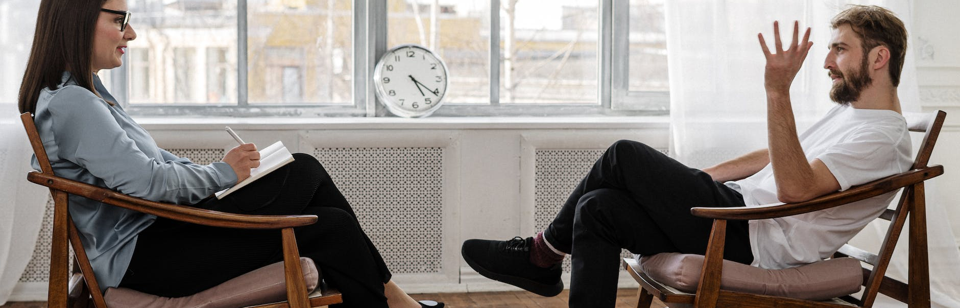 person in black pants and black shoes sitting on brown wooden chair